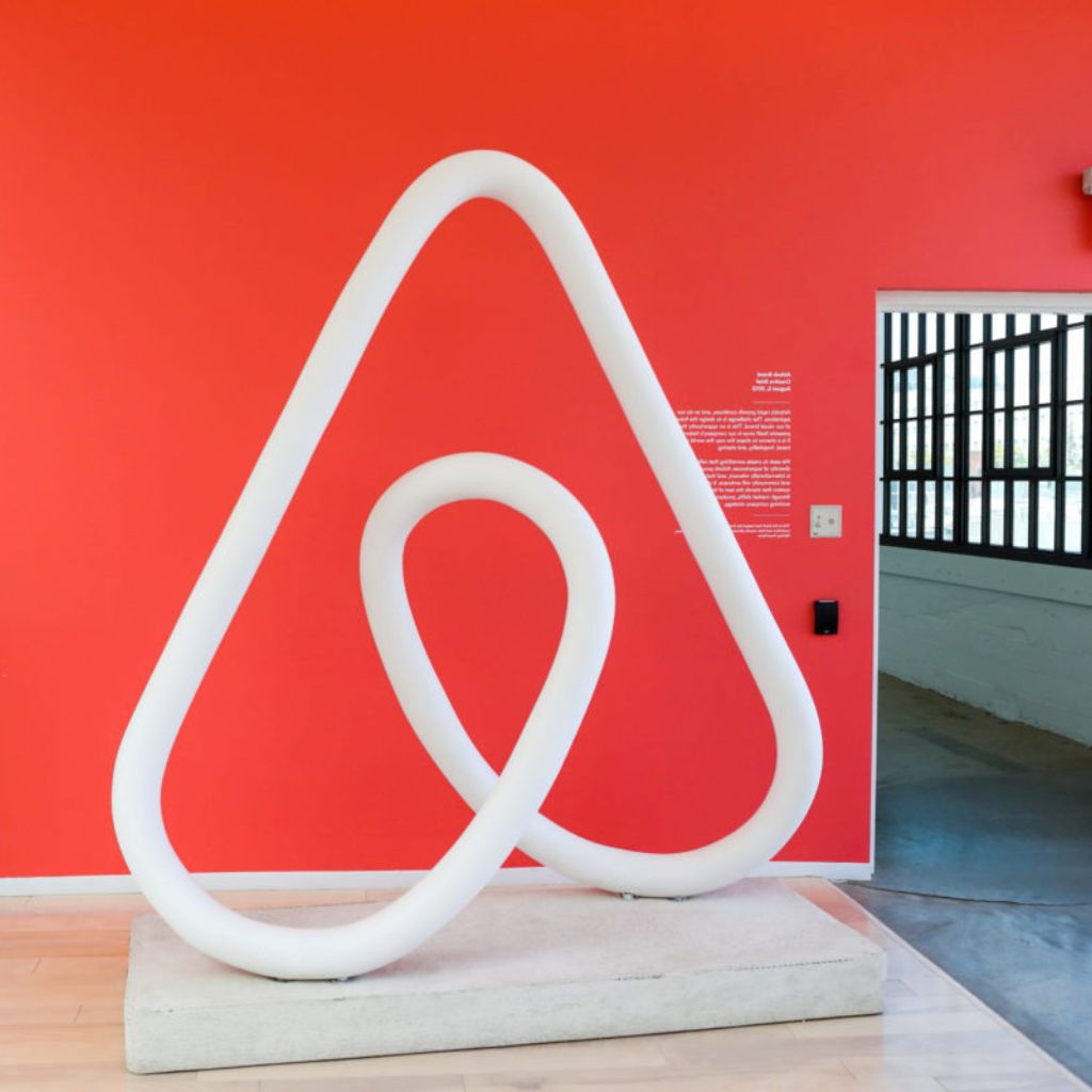 Logo neon light in front of a red wall - Compare Our Payment Terms to Other Platforms: Airbnb & Booking.com